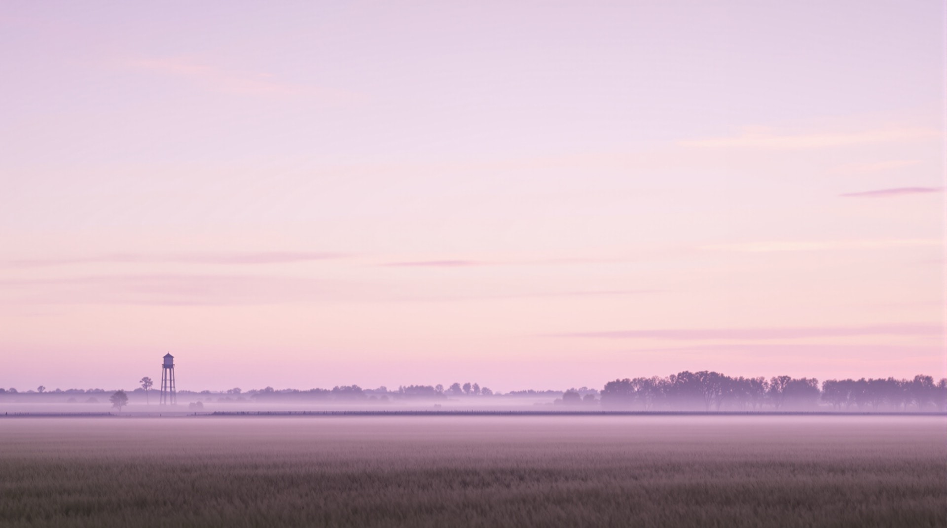 Kansas tallgrass prairie at first light with a distant water tower on the horizon